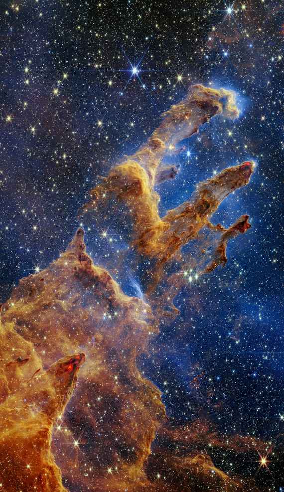 The Pillars of Creation are set off in a kaleidoscope of colour in the NASA/ESA/CSA James Webb Space Telescope’s near-infrared-light view. The pillars look like arches and spires rising out of a desert landscape, but are filled with semi-transparent gas and dust, and ever changing. This is a region where young stars are forming – or have barely burst from their dusty cocoons as they continue to form. Protostars are the scene-stealers in this Near-Infrared Camera (NIRCam) image. These are the bright red orbs that sometimes appear with eight diffraction spikes. When knots with sufficient mass form within the pillars, they begin to collapse under their own gravity, slowly heat up, and eventually begin shining brightly. Along the edges of the pillars are wavy lines that look like lava. These are ejections from stars that are still forming. Young stars periodically shoot out jets that can interact within clouds of material, like these thick pillars of gas and dust. This sometimes also results in bow shocks, which can form wavy patterns like a boat does as it moves through water. These young stars are estimated to be only a few hundred thousand years old, and will continue to form for millions of years. Although it may appear that near-infrared light has allowed Webb to “pierce through” the background to reveal great cosmic distances beyond the pillars, the interstellar medium stands in the way, like a drawn curtain. This is also the reason why there are no distant galaxies in this view. This translucent layer of gas blocks our view of the deeper universe. Plus, dust is lit up by the collective light from the packed “party” of stars that have burst free from the pillars. It’s like standing in a well-lit room looking out a window – the interior light reflects on the pane, obscuring the scene outside and, in turn, illuminating the activity at the party inside. Webb’s new view of the Pillars of Creation will help researchers revamp models of star formation.